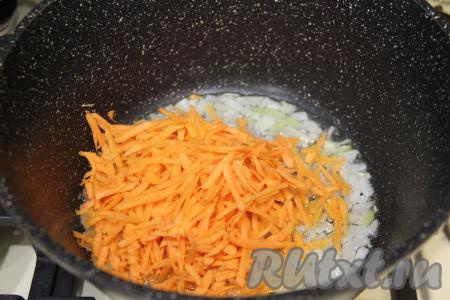 Обжарить лук 2-3 минуты, иногда помешивая, на среднем огне, затем выложить морковь, натёртую на крупной тёрке, перемешать овощи.