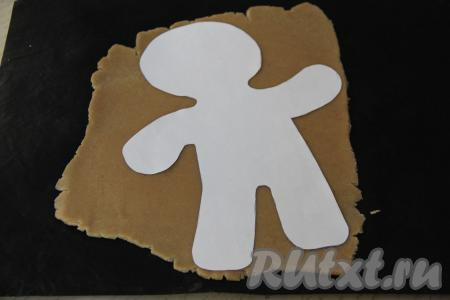 Охладившееся тесто раскатать в пласт толщиной примерно 5 миллиметров. Выложить трафарет на тесто и вырезать человечка. Я раскатывала тесто сразу на коврике для выпечки. Вместо коврика можно использовать пекарскую бумагу. Трафарет человечка предварительно вырезать из бумаги. Я нашла трафарет в Интернете, распечатала и вырезала на листе бумаги формата А4.