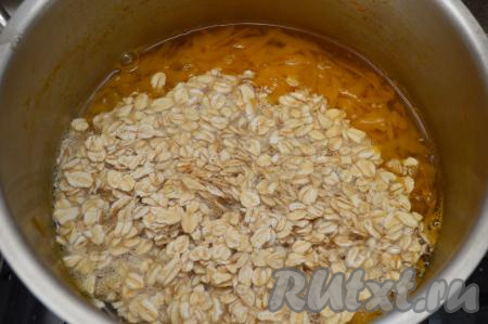 Всыпьте овсянку в кастрюлю с тыквой, перемешайте и варите на медленном огне в течение 5 минут.