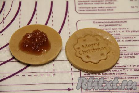 Вырезать из теста круглые заготовки (у меня - диаметром 8 сантиметров). Один кружок - это донышко, другой - верх пряника с рисунком. На одном кружке пропечатать любой рисунок (это можно сделать, например, с помощью вырубки для печенья, а можно просто сделать небольшой орнамент вилкой). В середину второго кружка выложить 1 чайную ложку повидла.