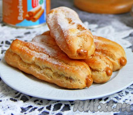 Варёную сгущёнку выложить в кулинарный мешок с круглой насадкой и наполнить остывшие эклеры. Если нет кулинарного мешка, можно сделать на эклере надрез, а затем с помощью ложки наполнить его сгущёнкой. Перед подачей можно присыпать эклеры сахарной пудрой.