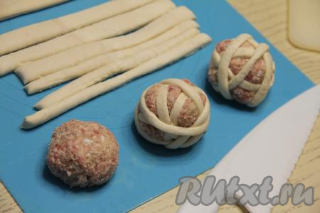 Скатать из каждой части фарша ровный мясной шарик. Каждый шарик из фарша обернуть несколькими полосками слоёного теста, как клубок ниток. Тесто не нужно предварительно раскатывать, просто во время обматывания слегка растягивать его.