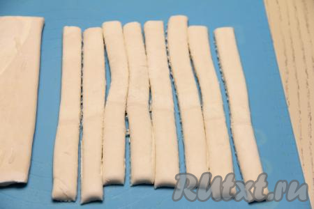 Разморозившееся слоёное тесто на слегка присыпанной мукой поверхности нарезать на полоски шириной примерно 1 сантиметр.