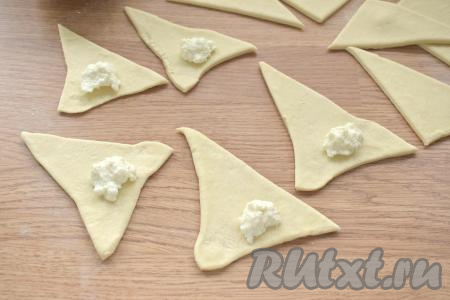 Берёмся за соседние концы треугольника, немного разводим их в сторону. Ближе к основанию треугольника, немного отступив от края, выкладываем почти чайную ложку творожной начинки.