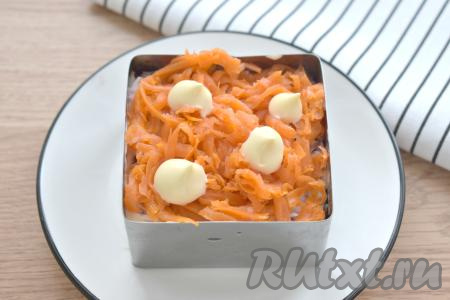 Следующим слоем раскладываем морковку, натёртую на крупной тёрке, покрываем её майонезом.