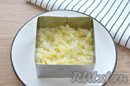 Заранее для салата нужно отварить в подсоленной воде куриное мясо, картошку, свеклу и морковь. Варёным овощам и мясу нужно дать полностью остыть. Остывшие свеклу, морковку и картошку очистить непосредственно перед формированием салата. Когда все ингредиенты будут подготовлены, можно приступать к сборке слоёного салата "Курица под шубой". Я формировала салат порционно, используя квадратную сервировочную форму со стороной 8 сантиметров, которую я поставила на плоскую тарелку (можно готовить и в одном салатнике). Количество ингредиентов представлено для двух порций салата, поэтому продукты я равномерно раскладывала по двум порционным формочкам. Очищенный варёный картофель натираем на крупной тёрке, раскладываем по двум формочкам, немного солим. Картошка станет первым слоем нашего салата.