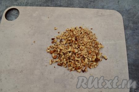 Грецкие орехи порубить ножом. Кусочки не нужно рубить очень мелко, но и крупными орешки быть не должны. Оставить несколько ядер грецких орехов целыми (я отложила для украшения очищенные ядра трёх грецких орехов) для украшения тарталеток.