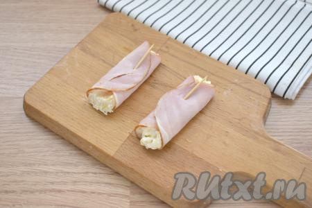 Накрываем начинку сначала одной стороной ломтика ветчины, затем сверху - второй. Фиксируем рулетик либо шпажкой, либо зубочисткой. Аналогично формируем остальные рулетики. Перекладываем их на блюдо и подаём к столу.