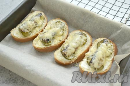 Отправляем бутерброды со шпротами и солёным огурцом в разогретую до 180 градусов духовку на 5-6 минут (до расплавления сыра).