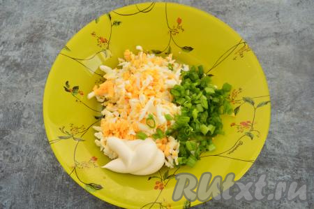 Перья зелёного лука вымыть, стряхнуть с них лишнюю жидкость, а затем мелко нарезать и добавить в тарелку с яйцами. Сюда же выложить майонез, перемешать яично-луковый салат, немного подсолить (сильно солить не нужно, ведь в дальнейшем будет выкладываться селёдка).