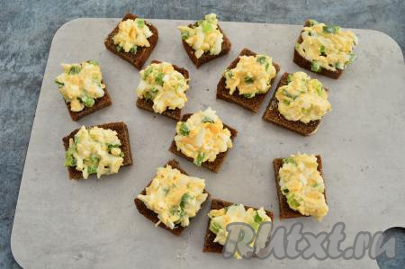 На квадратики чёрного хлеба разложить яично-луковый салат. Всего получается 12 небольших бутербродов.