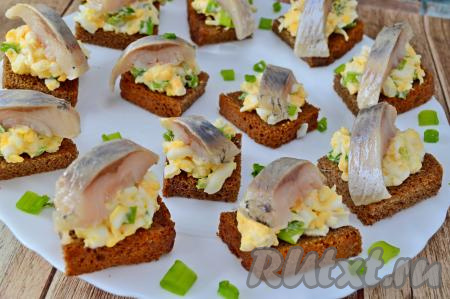 Разложить готовые бутерброды на плоское тарелку, которую можно слегка присыпать нарезанным зелёным луком.