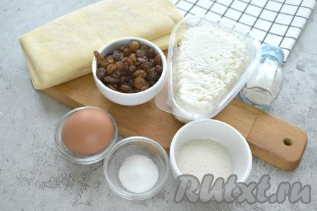 Подготовим продукты для нашего пирога с творогом. Слоёное дрожжевое тесто заранее достаём из морозилки и оставляем его размораживаться при комнатной температуре. Изюм перебираем, удаляем лишний мусор и хвостики.
