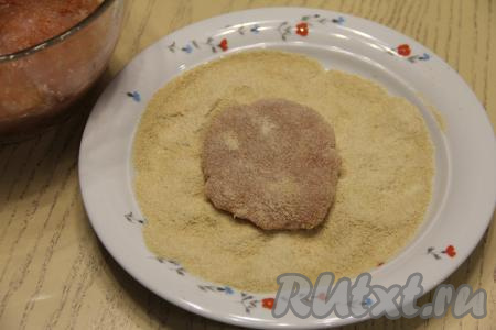 На плоскую тарелку насыпать панировочные сухари. Разделить фарш на 10-12 частей. Из каждой части фарша сформировать плоскую лепёшку толщиной 1 сантиметр и обвалять её в панировочных сухарях с двух сторон. Не нужно делать лепёшки абсолютно круглыми, ведь шницели из мяса по краям неровные.