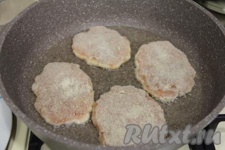 В сковороду влить растительное масло и хорошо разогреть. Выложить шницели из куриного фарша в панировке в разогретое масло.