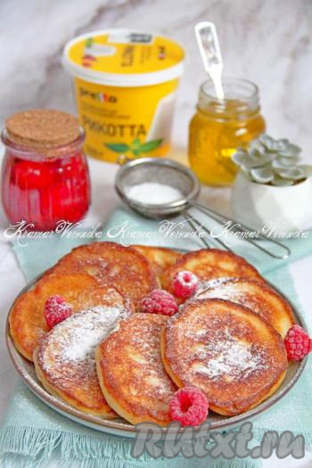 Вкусные, нежные, аппетитные оладьи, приготовленные с добавлением рикотты, подать к столу тёплыми, посыпав сахарной пудрой или дополнив мёдом, вареньем, сметаной.