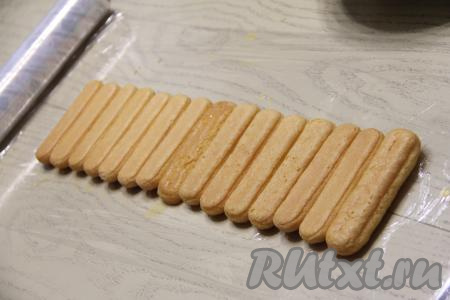 На столе расстелить пищевую плёнку (или прозрачный полиэтиленовый пакет). Выложить савоярди, пропитанное мандариновым соком, в один ряд вплотную друг к другу на пищевую плёнку. Я выложила 15 штук. Можно конечно выложить все 25 печенюшек, но я решила сэкономить плёнку.