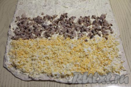 Немного отступив от краёв лаваша, выложить натёртые яйца широкой полоской. Рядом сделать полоску из сельди.