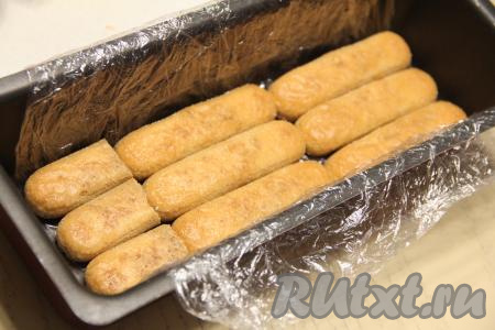 Дно и бока формы, в которой вы будете формировать тирамису (я формировала в металлической форме для хлеба), застелить пищевой плёнкой так, чтобы края плёнки свисали с краёв формы. Окунать печенье "Савоярди" в остывший кофе с двух сторон и выкладывать в форму в один слой.