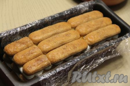 Сверху разложить второй слой печенья "Савоярди", пропитанного кофе с двух сторон. Печенье покрыть третью крема из маскарпоне и сливок, сверху нанести полоски из оставшегося ягодное пюре. Затем выложить последний слой из савоярди, тоже пропитанного кофе с двух сторон.