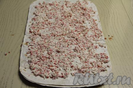 Сверху выложить третий лист лаваша, смазать его крабовой начинкой, тоже немного отступив от краёв лаваша.