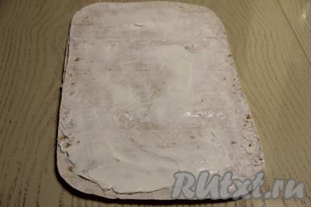 Накрыть начинку вторым листом лаваша, смазать его плавленным сыром, тоже немного отступив от краёв лаваша.