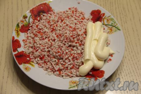 Крабовые палочки мелко нарезать, переложить в глубокую тарелку, добавить 3 столовых ложки майонеза, перемешать.