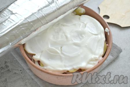 Сверху смазываем картошку сметаной. Форму накрываем фольгой и отправляем в разогретую до 180 градусов духовку.