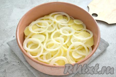 Очищаем лук, нарезаем его на тонкие кольца. Половину нарезанного лука выкладываем поверх картошки.