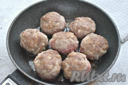 Разогреваем на сковороде растительное масло. Выкладываем в горячее масло заготовки тефтелей и обжариваем их на среднем огне до подрумянивания с двух сторон (примерно по 2 минуты с каждой стороны). Благодаря обжариванию тефтели будут лучше держать форму при запекании в духовке в томатном соусе.