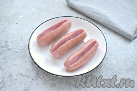 Достаём сосиски из кастрюли, перекладываем на тарелку, даём немного остыть. По середине по всей длине каждой сосиски делаем глубокий надрез.