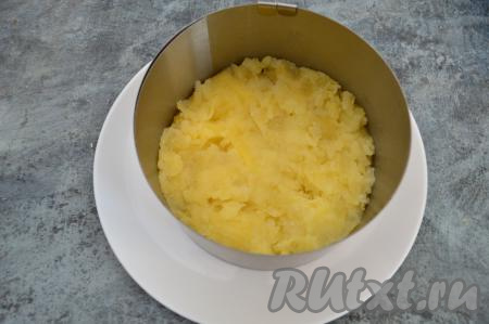 Формировать салат "Иваси под шубой" будем слоями, используя кулинарное кольцо. Кольцо установить на плоскую тарелку. Картошку очистить, натереть на крупной тёрке, подсолить, перемешать и выложить ровным слоем в кулинарное кольцо. Я использовала кольцо диаметром 16 сантиметров, салат получился высоким, можно сделать его более плоским, для этого нужно взять кольцо диаметром 20 сантиметров.