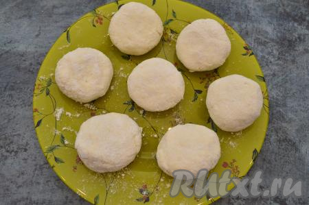 Выложить заготовки сырников на плоскую тарелку и немного прижать ладонью, чтобы придать сырникам более плоскую форму.