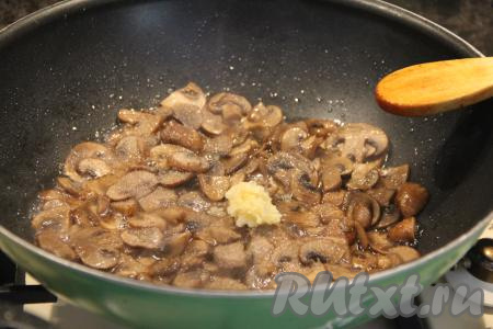 После того как грибы обжарятся в течение 15 минут, добавить к ним очищенный и пропущенный через пресс чеснок, перемешать.