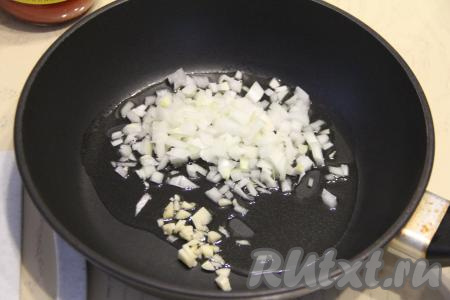 В сковороду влить растительное масло, разогреть, выложить мелко нарезанные лук и чеснок, обжарить их, иногда помешивая, в течение 3-4 минут (до мягкости лука) на среднем огне.