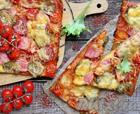 Достать готовую выпечку из духовки, нарезать на кусочки и подать аппетитную, сочную пиццу к столу. Солёный огурец придаёт этой выпечке особую пикантность и приятный вкус. Обязательно попробуйте пиццу из слоёного теста с такой начинкой!