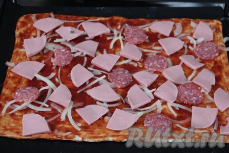 Лук нарезать на тонкие полукольца и выложить на тесто. Колбасу (у меня - колбаса двух видов) тонко нарезать. Крупные кусочки колбаски нарезать на части и выложить на тесто.&nbsp;