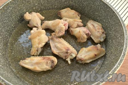 Вливаем в глубокую сковороду растительное масло и разогреваем его на среднем огне в течение минуты. Выкладываем куриные крылышки на сковороду и обжариваем их с каждой стороны по 3 минуты.