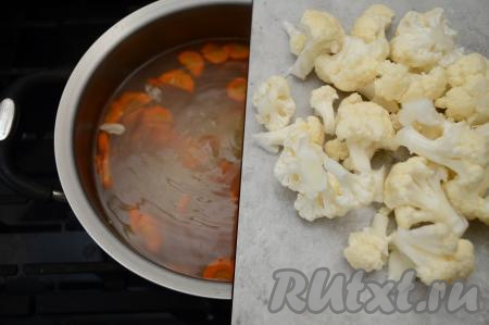 После того как бульон с куриным мясом закипит, добавить в кастрюлю нарезанные морковку и картошку, дать закипеть, и, убавив огонь до минимума, варить суп 10-12 минут. Затем добавить в суп цветную капусту, посолить, дать закипеть, варить на небольшом огне 5 минут.