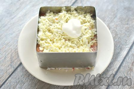 Следующим слоем раскладываем по формам желтки, натёртые на крупной тёрке, покрываем их майонезом.