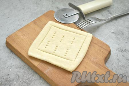 Каждый квадратик теста слегка раскатываем на присыпанной мукой поверхности. С помощью пиццерезки или острого ножа делаем на квадратах надрезы по периметру, отступив от краёв по 1 сантиметра. В центре делаем проколы вилкой.