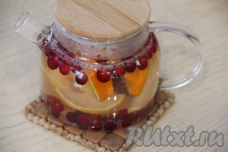 Залить апельсины, лимоны и клюкву 500 миллилитрами кипящей воды, закрыть заварник крышкой. Накрыть чайник с чаем полотенцем и оставить на минут 10.