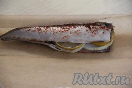 В брюшко скумбрии вложить кружочки лука и лимона.