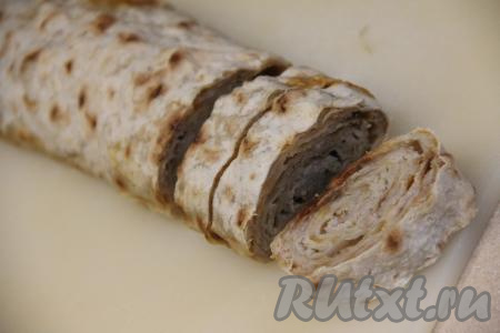 Запекать рулет из лаваша с фаршем и сыром в духовке минут 40 при температуре 220 градусов. Готовый рулет достать из духовки, немного остудить, снять фольгу и пергамент. Затем дать рулету остыть и нарезать острым ножом на кусочки толщиной 1,5 сантиметра.