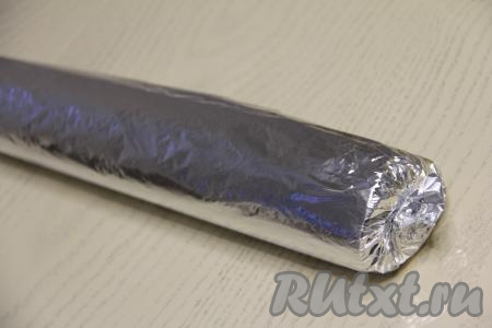 Сначала завернуть рулет в пергамент, а затем - в фольгу. Переложить завёрнутый рулет на противень и поместить в разогретую духовку.