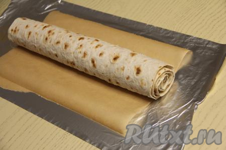 Свернуть лаваш с начинкой в плотный рулет, начиная с узкой стороны лаваша. Выложить рулет на лист пергамента.