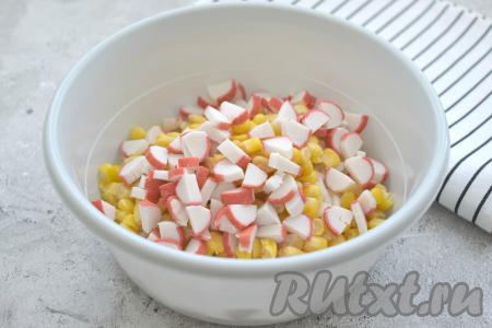 С крабовых палочек снимаем упаковку, нарезаем их на небольшие кубики, добавляем в салат из риса и кукурузы.