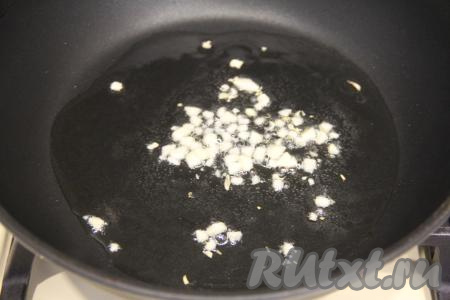 В сковороду влить растительное масло, хорошо прогреть его, выложить мелко нарезанный чеснок и обжарить его 1 минуту, периодически помешивая.