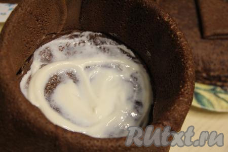 Смазать первый блин, выложенный на дно формы, частью сметанного крема.