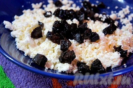 Чернослив (или изюм, или курагу) промыть, обдать кипятком, обсушить на бумажном (или тканевом) полотенце. К творогу добавить мелко нарезанный чернослив (или изюм, или нарезанную курагу), перемешать.